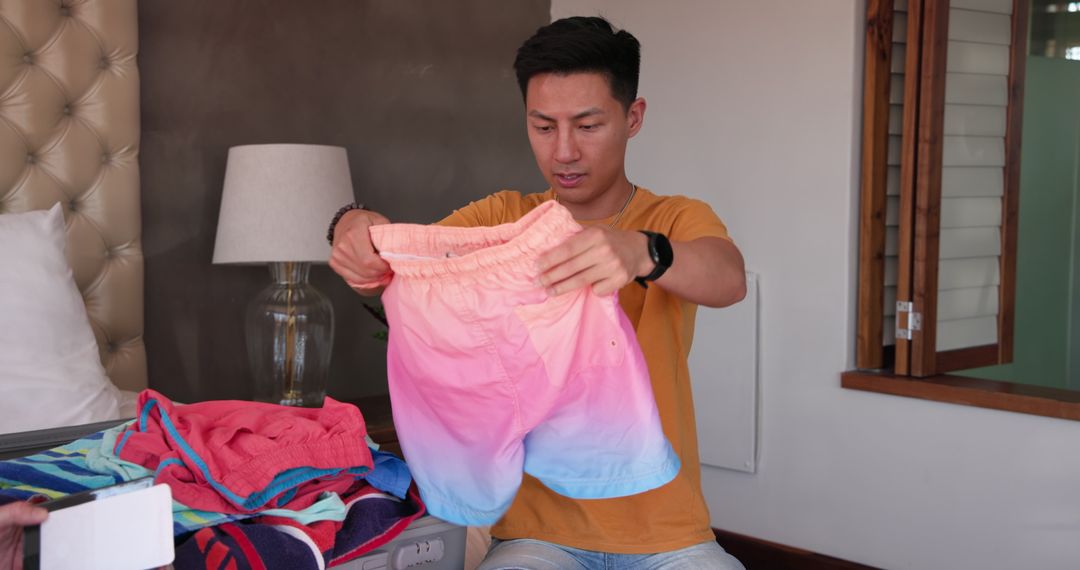 Man Packing Colorful Shorts in Suitcase for Vacation