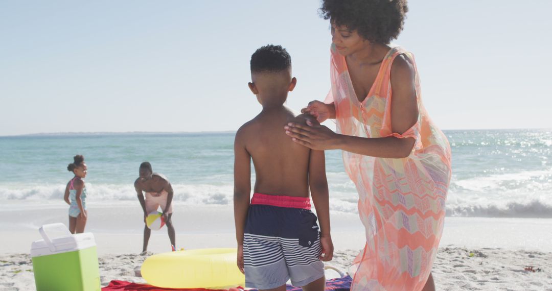 Mother Applying Sunscreen to Son at Beach on Sunny Day - Free Images, Stock Photos and Pictures on Pikwizard.com