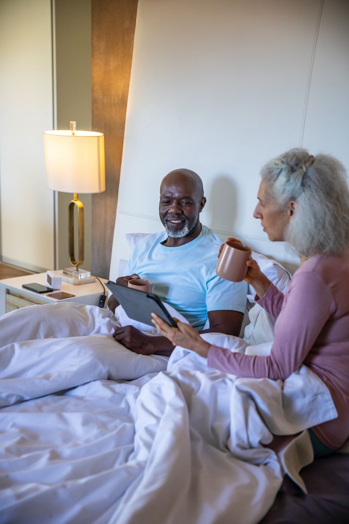 Senior Couple Relaxing with Tablet and Coffee in Bed