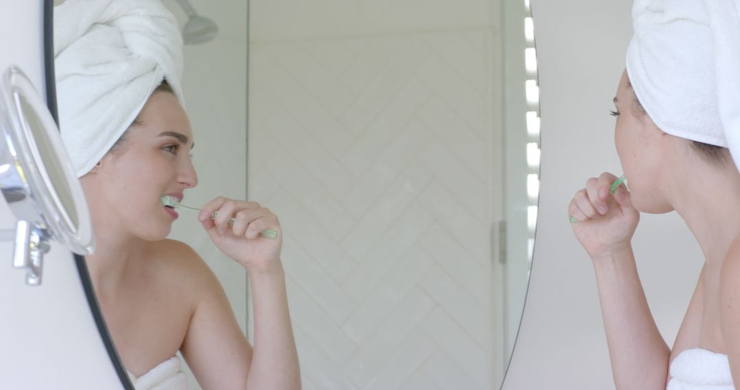 Woman Brushing Teeth with Towel Wrapped Around Head in Modern Bathroom - Free Images, Stock Photos and Pictures on Pikwizard.com