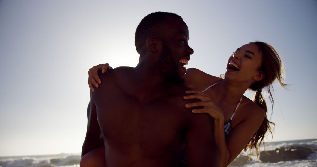 Interracial Couple Enjoying Piggyback Ride on Beach During Sunset - Free Images, Stock Photos and Pictures on Pikwizard.com