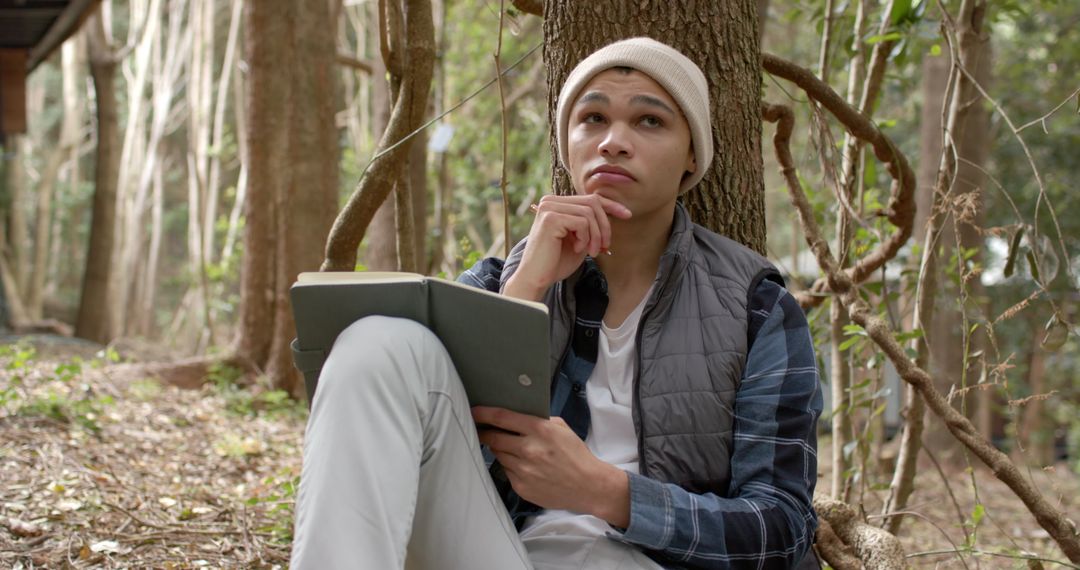 Thoughtful Man Relaxing with Notebook in Peaceful Forest