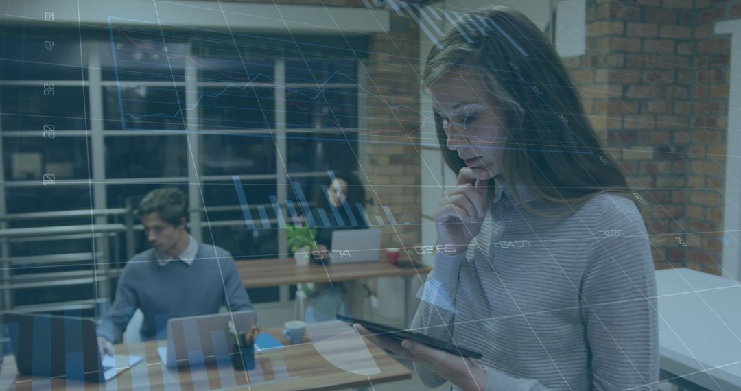 Businesswoman Analyzing Data on Tablet with Team Working in Office