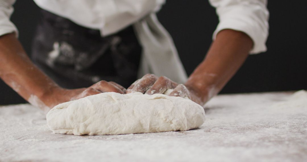 Chef Kneading Dough on Floured Surface in Kitchen