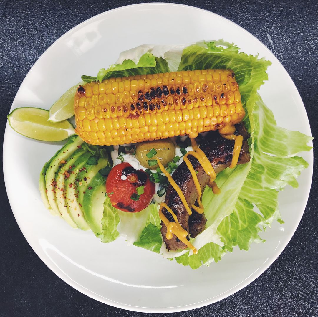 Grilled Corn and Sausage Plate with Sliced Avocado, Charred Tomato and Lime