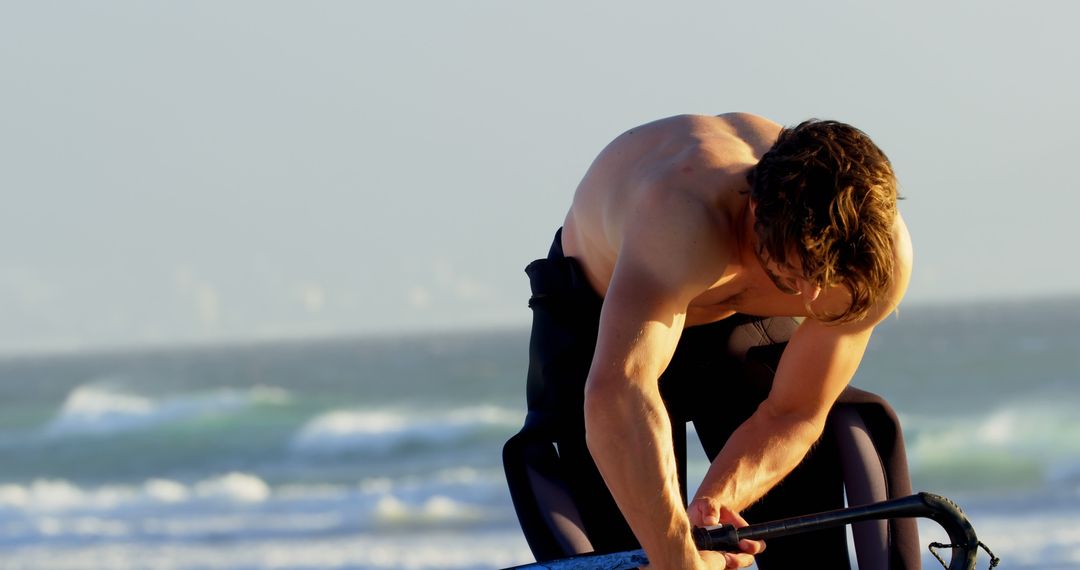 Muscular Man Prepares Surf Board on Sunny Beach - Free Images, Stock Photos and Pictures on Pikwizard.com