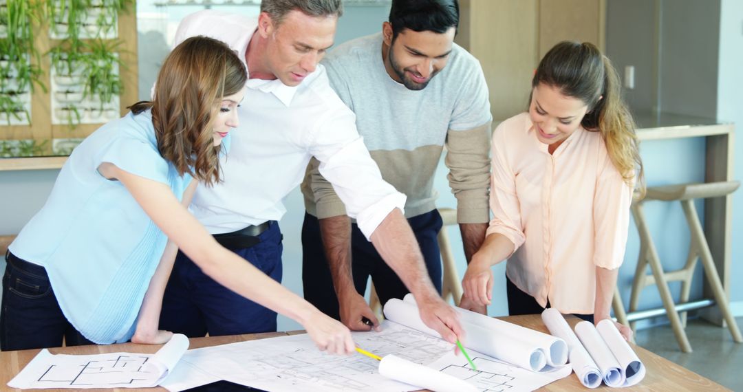 Team Analyzing Blueprints at Modern Office Table