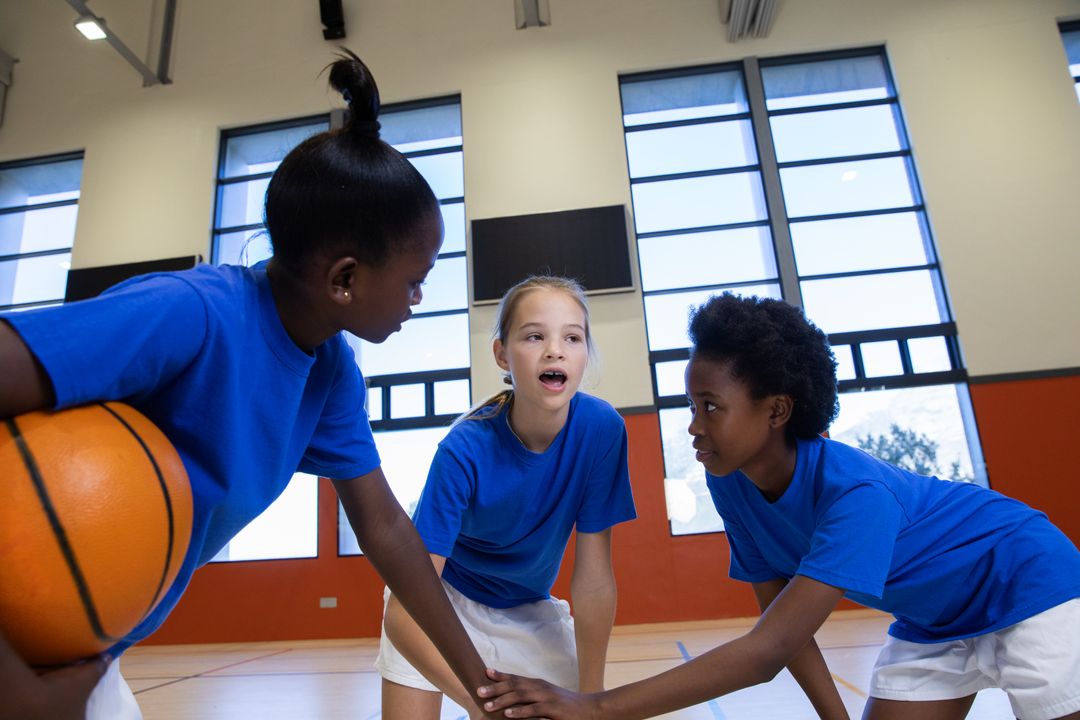 Diverse Youth Basketball Team Huddling with Ball in Gym
