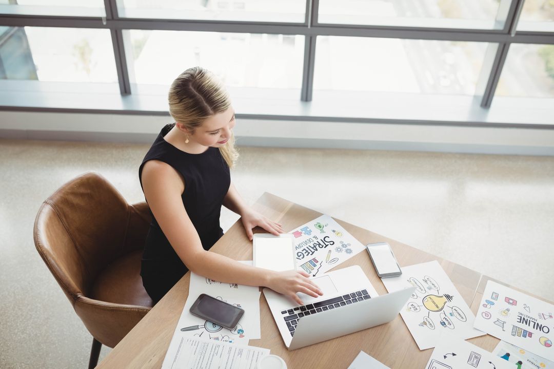 Business Professional at Minimalist Workspace with Laptop and Sketches