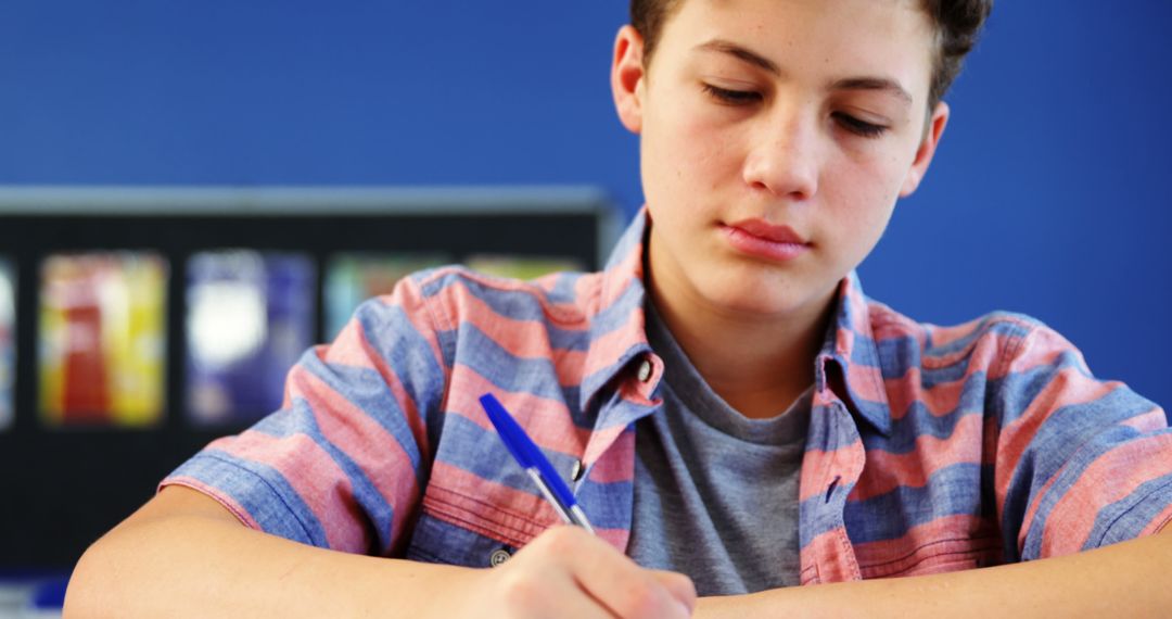 Teen Boy Concentrating On Writing In Classroom - Free Images, Stock Photos and Pictures on Pikwizard.com