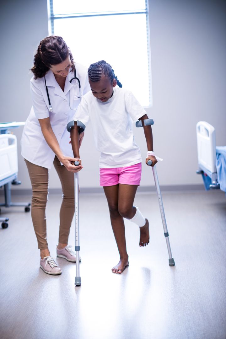 Female doctor assisting girl to walk with crutches in ward - Free Images, Stock Photos and Pictures on Pikwizard.com