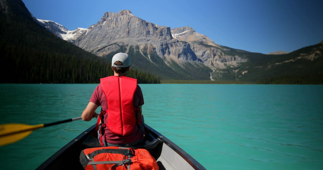 Man Canoeing on Turquoise Lake with Mountain Backdrop - Free Images, Stock Photos and Pictures on Pikwizard.com