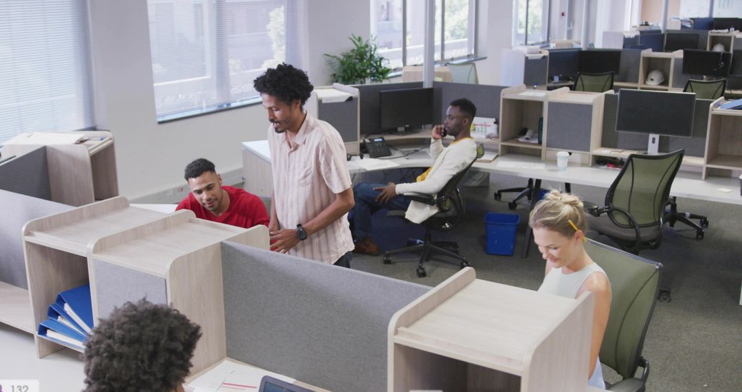 Casual Team Collaborating in Modern Open-Plan Office, Coworkers Using Laptops and Phone