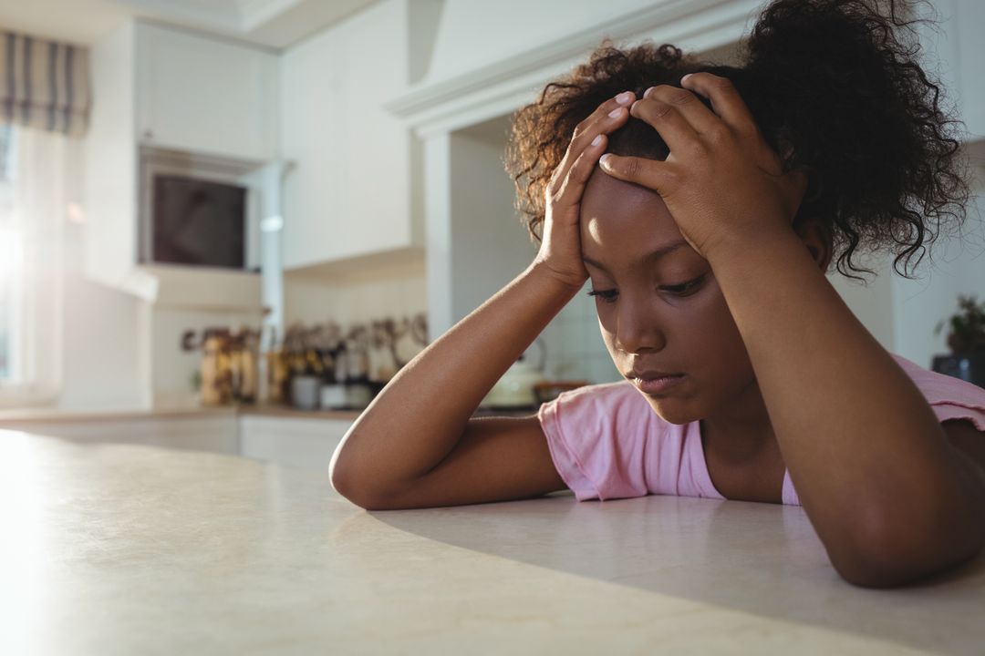 Pensive Child in Kitchen Leaning on Counter