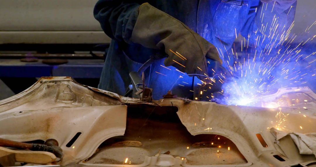 Welder Repairing Auto Panel with Sparks and Glow in Workshop