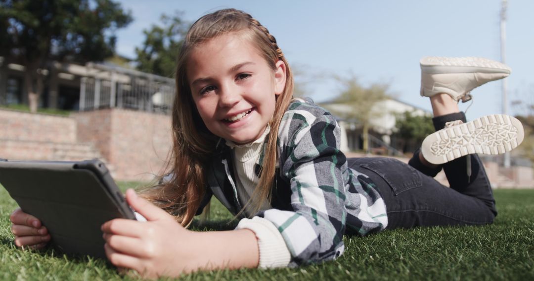 Smiling Girl Using Tablet While Relaxing on Grass