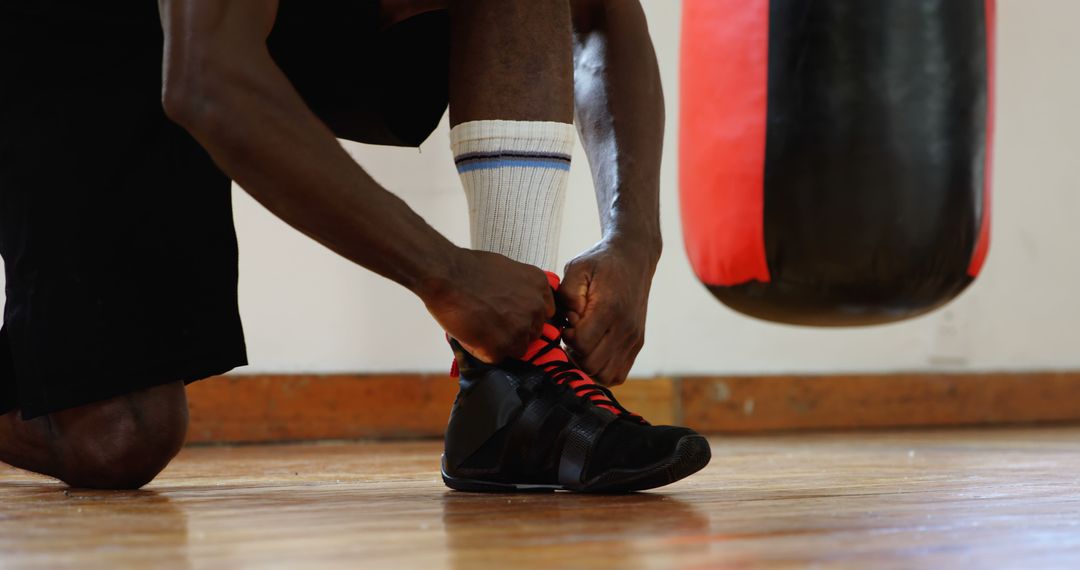 Athlete Tying Boxing Shoes Next to Red Punching Bag - Free Images, Stock Photos and Pictures on Pikwizard.com