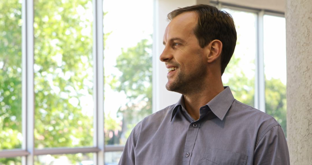 Middle-Aged Man Smiling Casually Near Large Windows - Free Images, Stock Photos and Pictures on Pikwizard.com