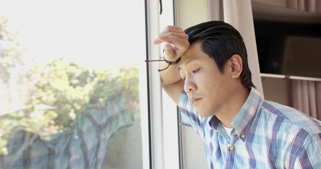 Contemplative Asian Man Gazing Through Window in Tranquil Home