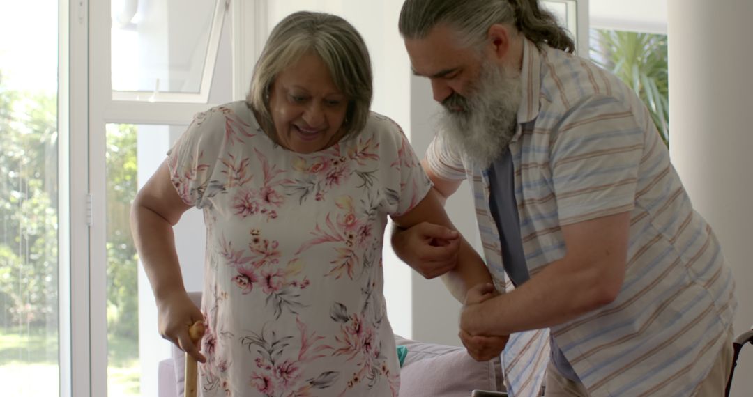 Elder man assisting senior woman with walking cane for mobility support