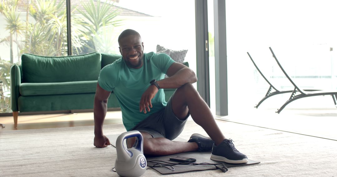 Smiling Man Exercising at Home with Kettlebell and Resistance Bands