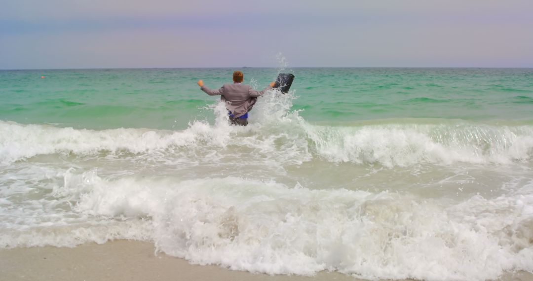 Businessman Running with Briefcase into Sea Waves at Beach