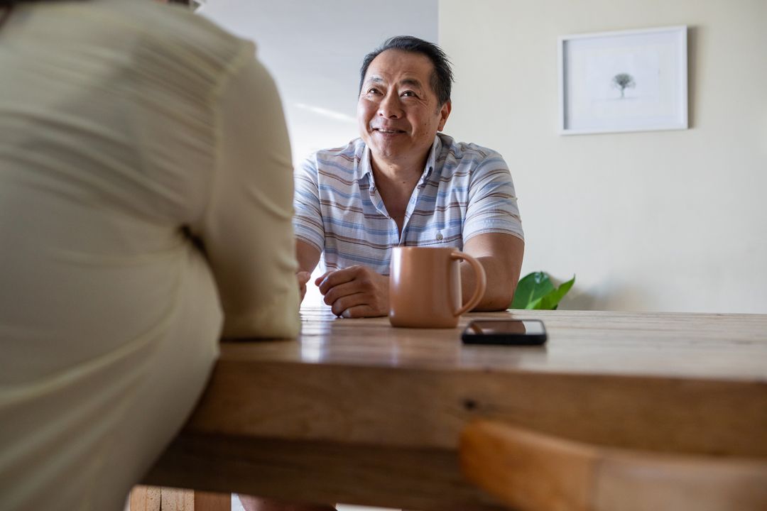 Mature Man Enjoying Conversation with Friend at Dining Table