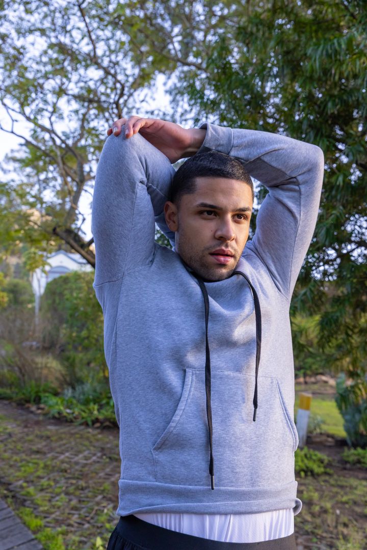 Man Stretching in Backyard with Grey Hoodie for Workout Warm-up