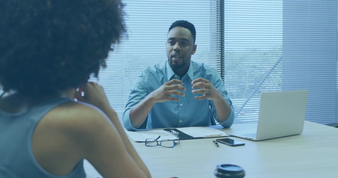 Manager Gesturing During Job Interview at Office Table With Laptop and Documents