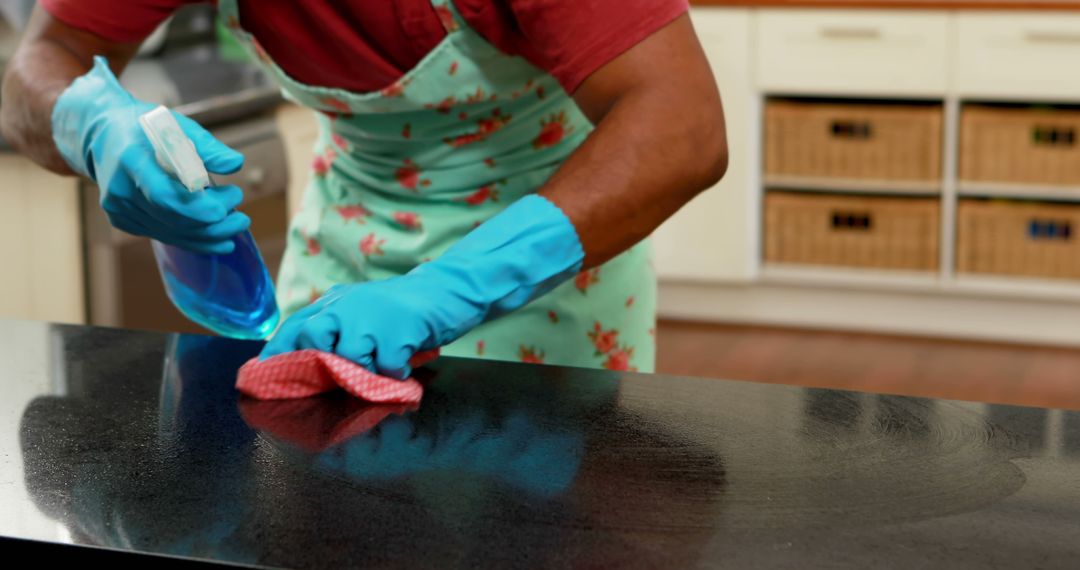 A person is cleaning a kitchen countertop with a spray bottle and cloth, with copy space - Free Images, Stock Photos and Pictures on Pikwizard.com