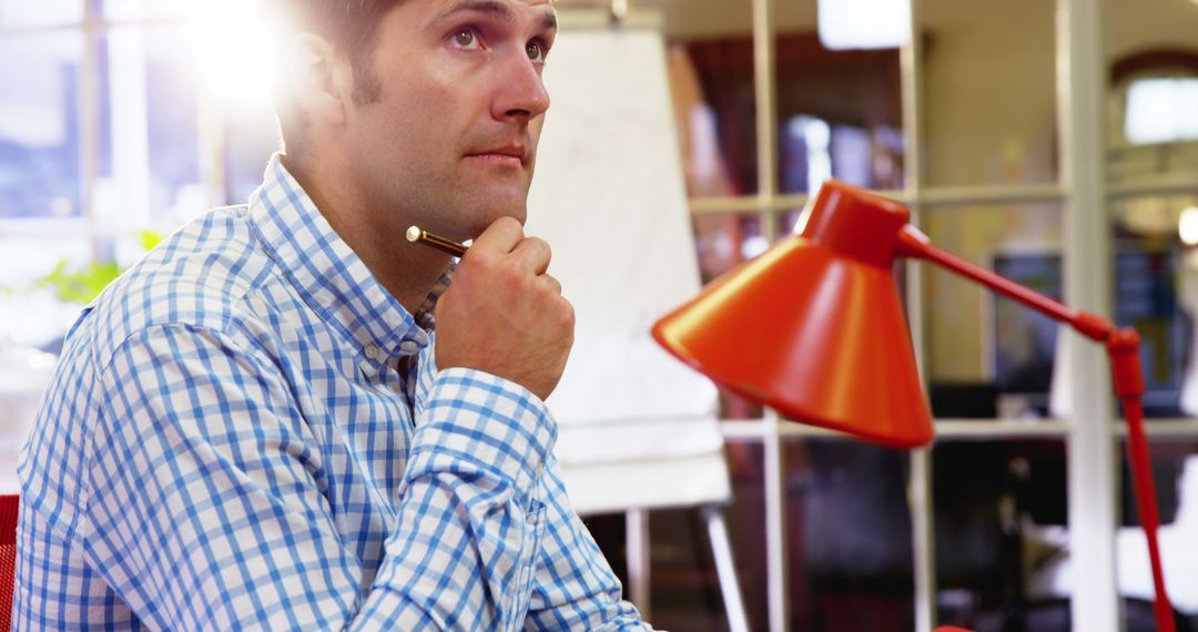 Businessman Pondering Ideas in Office with Pen in Hand - Free Images, Stock Photos and Pictures on Pikwizard.com