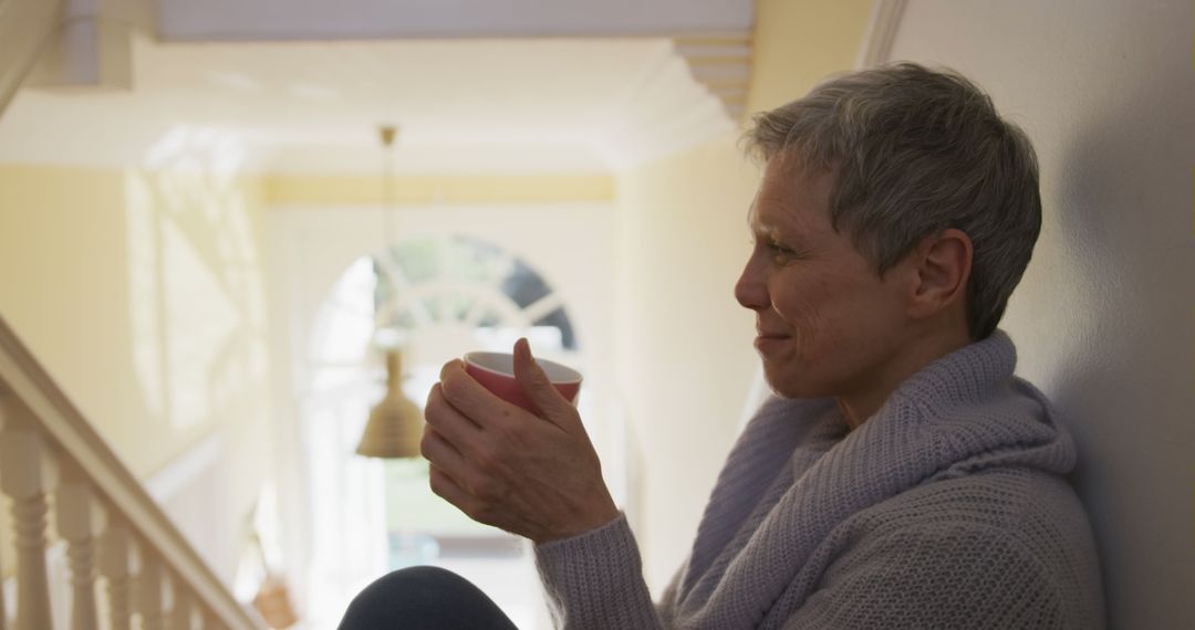 Older Woman Sipping Tea on Staircase in Cozy Home - Free Images, Stock Photos and Pictures on Pikwizard.com