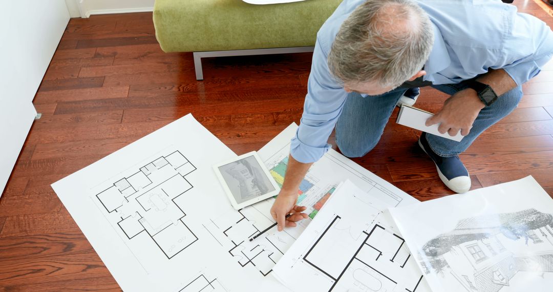 Architect Reviewing House Plans and Blueprints on Wooden Floor - Free Images, Stock Photos and Pictures on Pikwizard.com