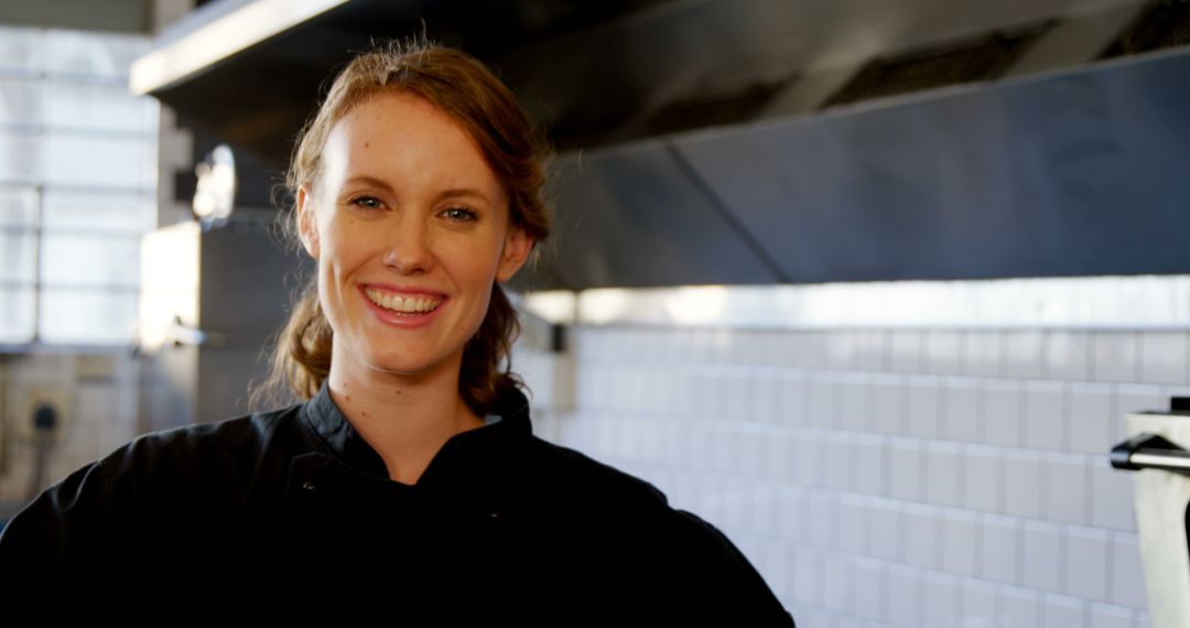 Female Chef Smiling in Commercial Kitchen with White Tiled Wall - Free Images, Stock Photos and Pictures on Pikwizard.com