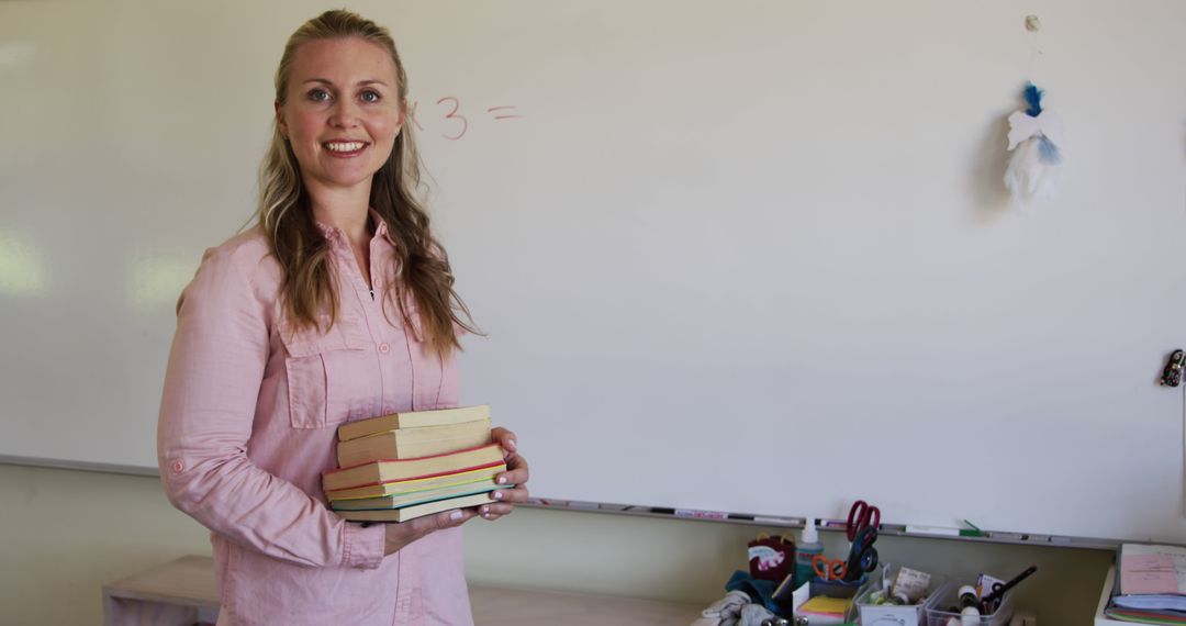 Smiling Female Teacher Holding Books in Classroom - Free Images, Stock Photos and Pictures on Pikwizard.com