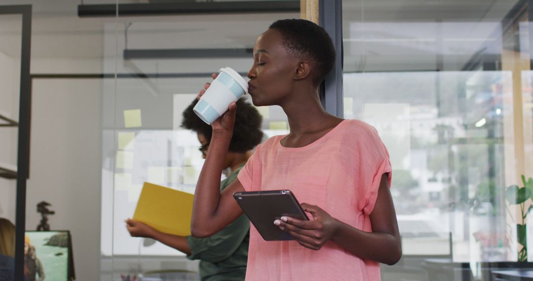 Confident Businesswoman Drinking Coffee While Using Tablet in Office