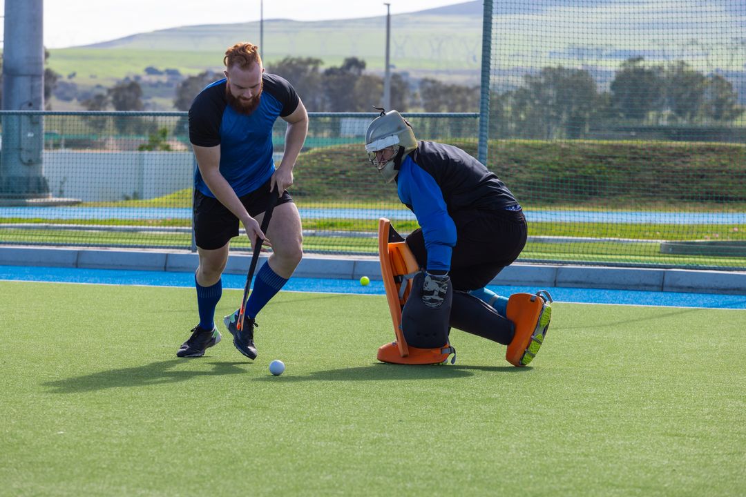 Intensity on Field Hockey Pitch with Competitive Duo Facing Goalkeeper