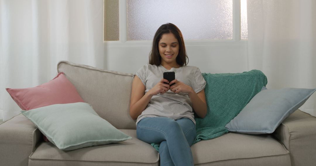 Young Woman Relaxing on Couch and Texting on Mobile Phone - Free Images, Stock Photos and Pictures on Pikwizard.com