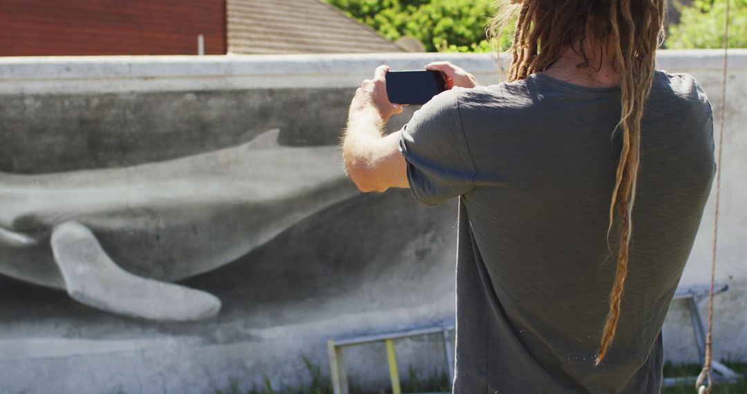 Person with Dreadlocks Capturing Street Art on Smartphone - Free Images, Stock Photos and Pictures on Pikwizard.com