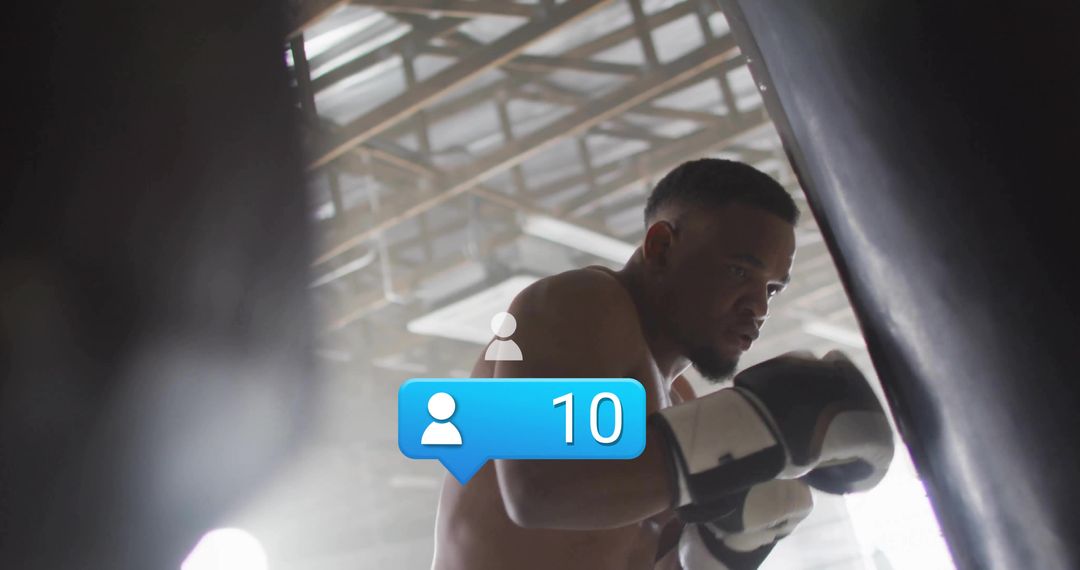 Boxer training on heavy bag, displaying focus and grit, wearing gloves and wraps in industrial gym