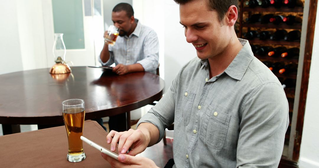 Man Enjoying Drink and Using Tablet in Cafe - Free Images, Stock Photos and Pictures on Pikwizard.com