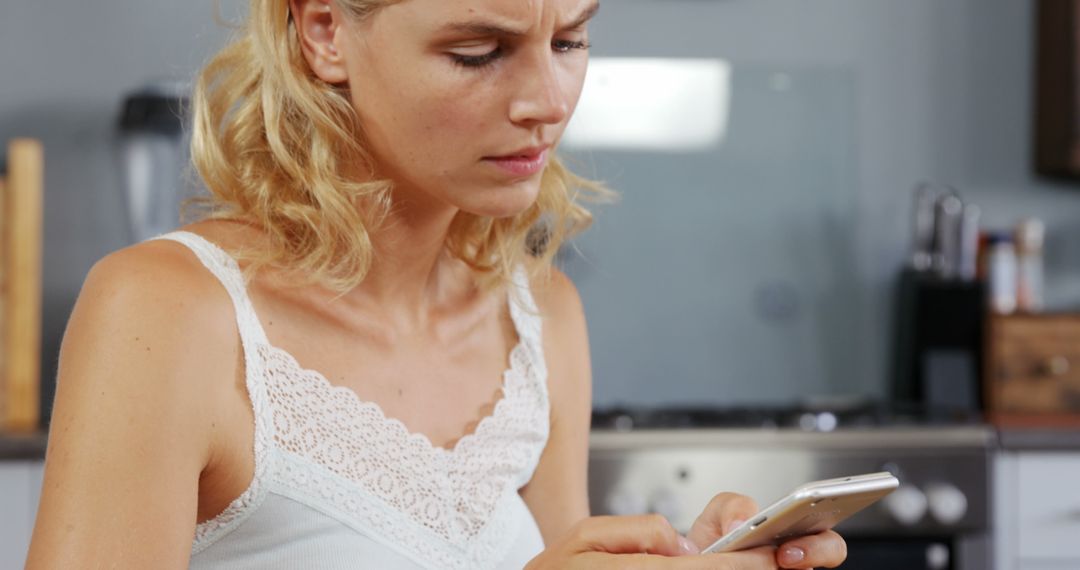 Concerned Woman Using Smartphone in Modern Kitchen - Free Images, Stock Photos and Pictures on Pikwizard.com