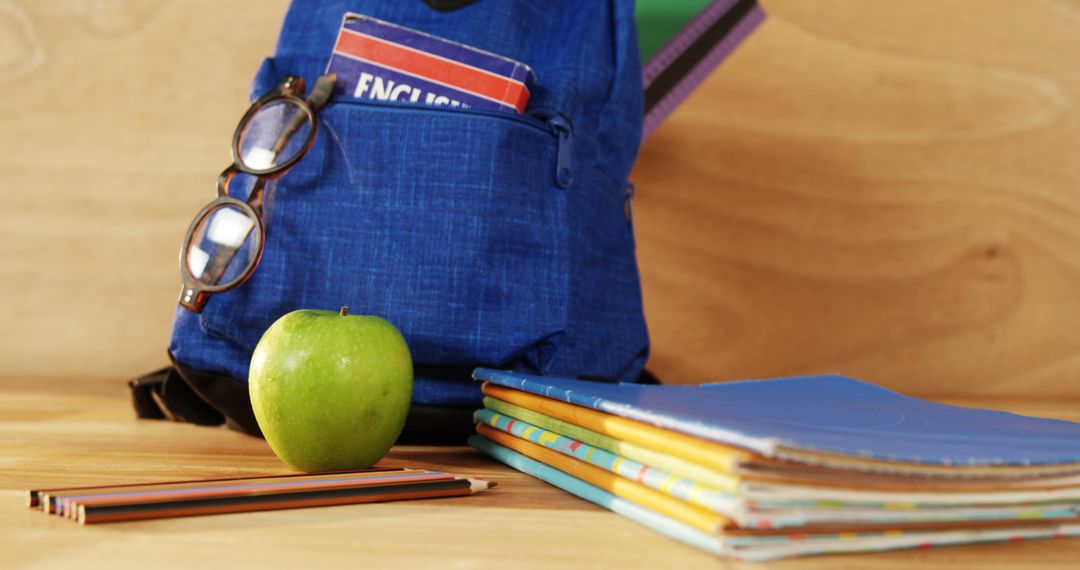 School Essentials with Green Apple and Colorful Books on Desk
