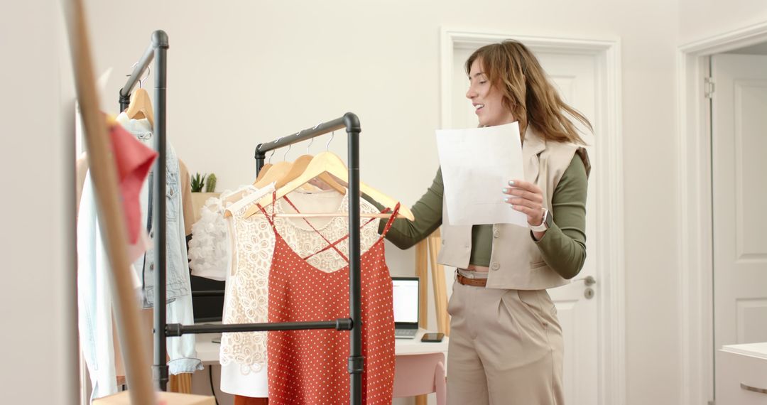 Fashion Stylist Organizing Clothing Rack in Minimal Home Studio Holding Order Sheet