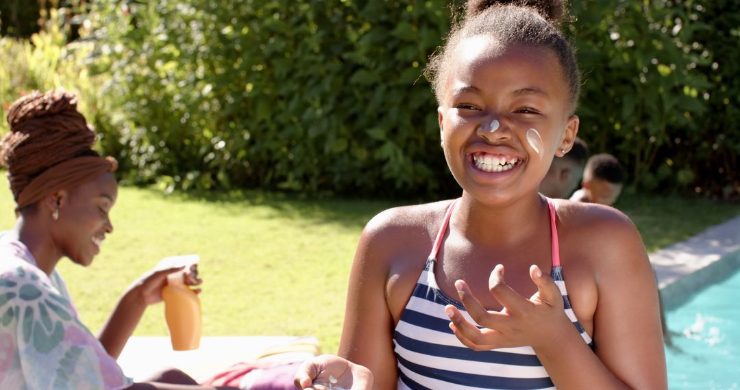 Smiling Girl Applying Sunscreen Beside Pool with Family in Summer