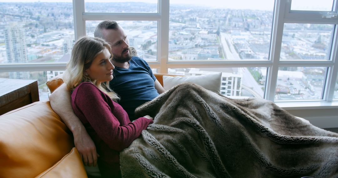 Couple Relaxing on Couch with City Skyline View - Free Images, Stock Photos and Pictures on Pikwizard.com