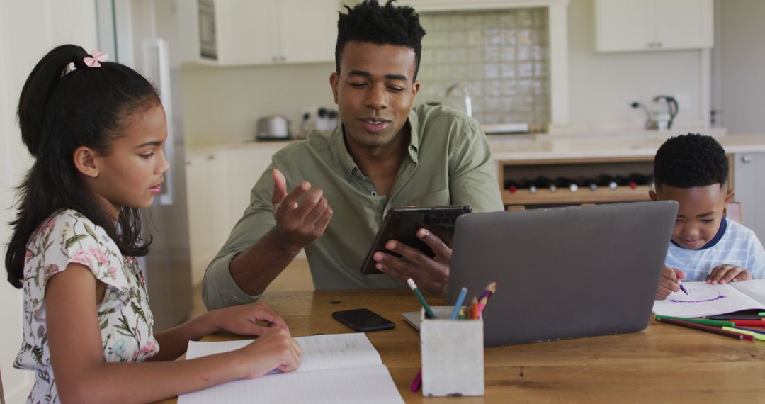 African American father helping children with homework at kitchen table - Free Images, Stock Photos and Pictures on Pikwizard.com