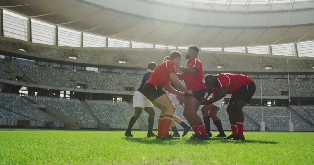 Rugby players forming scrum in large stadium under bright sunlight