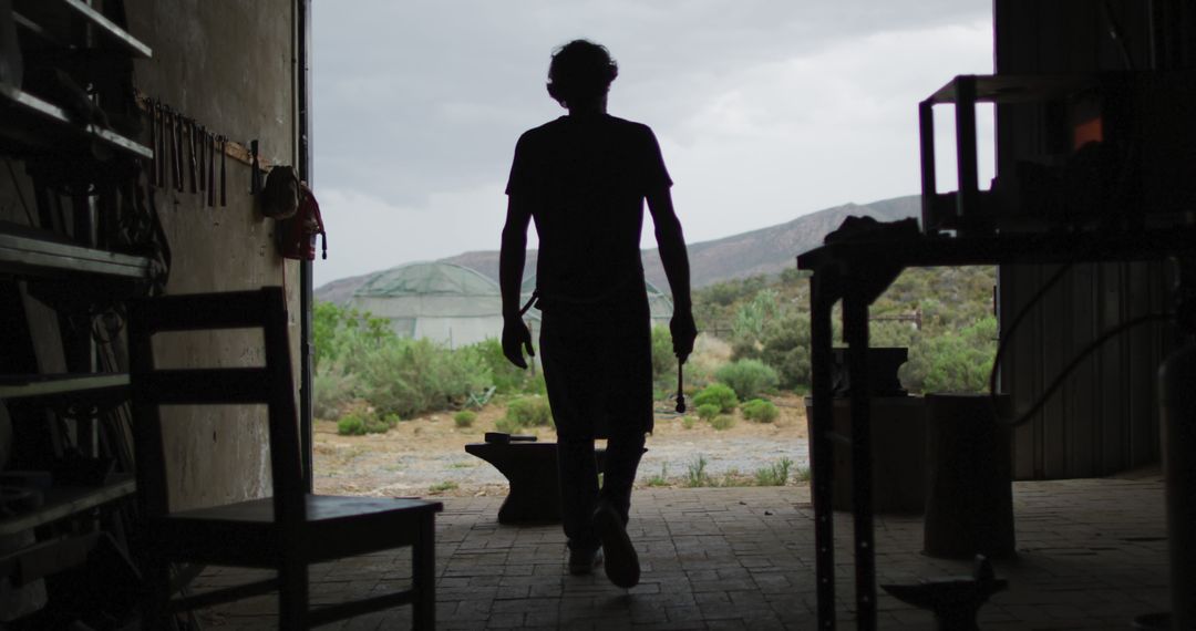 Silhouette of Man Walking Through Workshop to Outdoor Setting - Free Images, Stock Photos and Pictures on Pikwizard.com