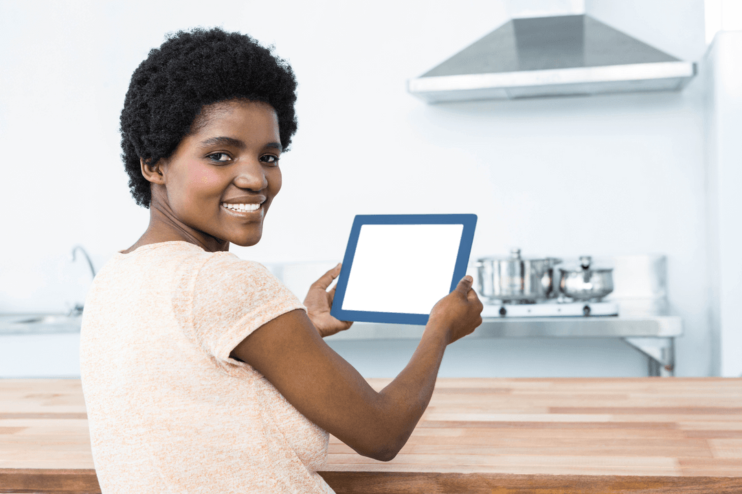 Smiling African American Woman Holding Transparent Tablet in Modern Kitchen